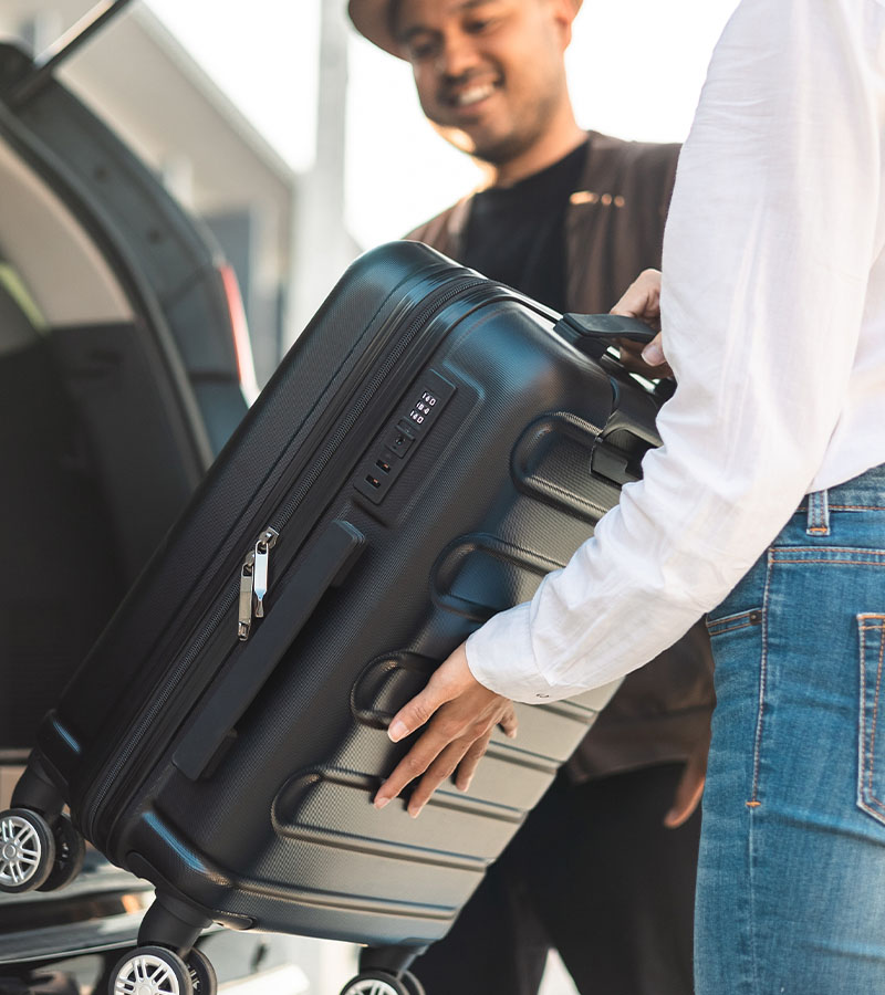 Chauffeur putting suitcase in car trunk